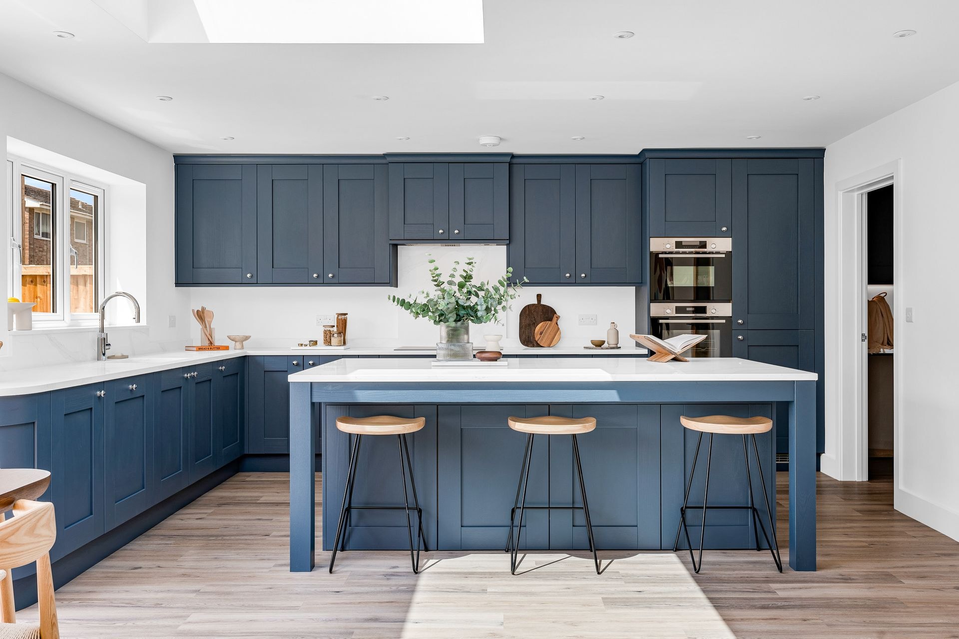 Navy shaker kitchen with a white quartz island and three bar stools in a completed Branksome Avenue home.