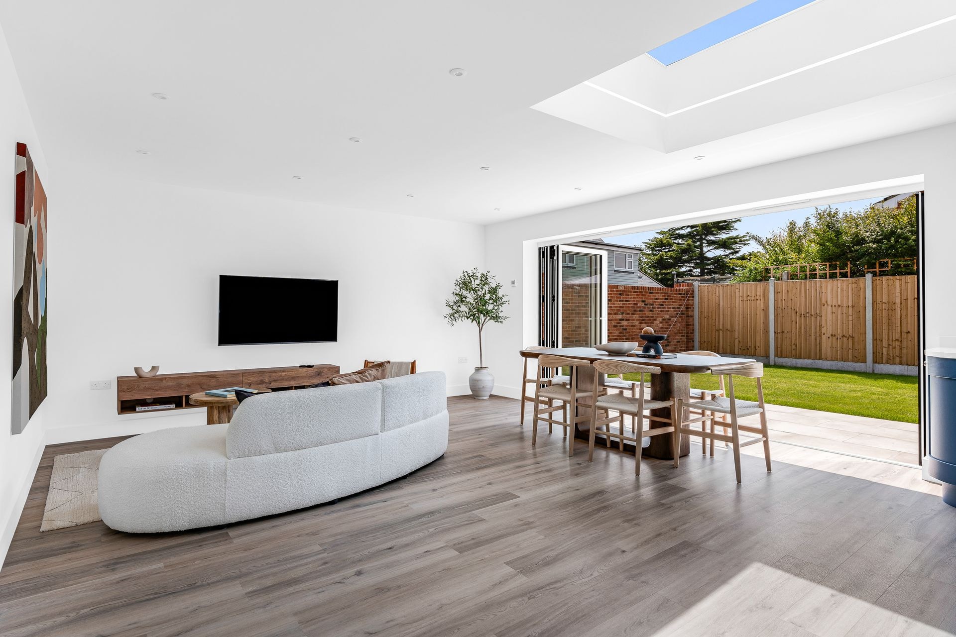 Open-plan living room with a curved sofa, wood floor and bi-fold doors open to the garden.